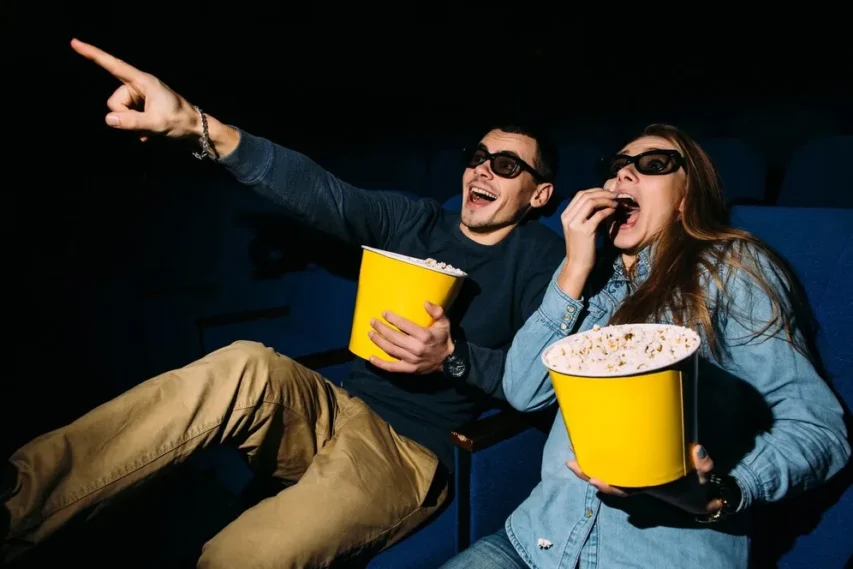 Risos Garantidos: A Magia da Comédia no Cinema Que Todos Amamos 1 casal no cinema rindo e comendo pipoca